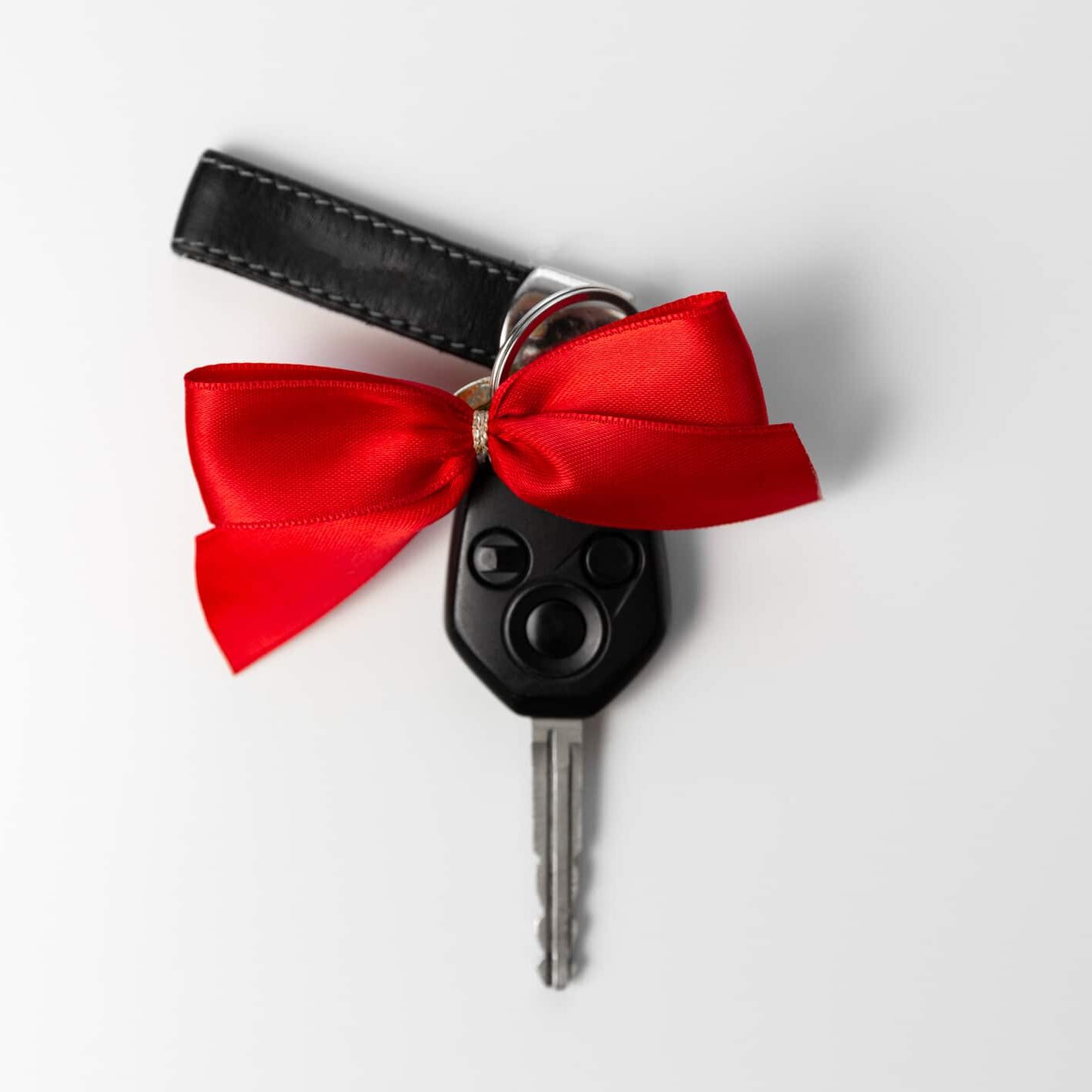 Car keys with red bow as present on white background. New car gift concept Car keys with red bow as present on white background. New car gift concept